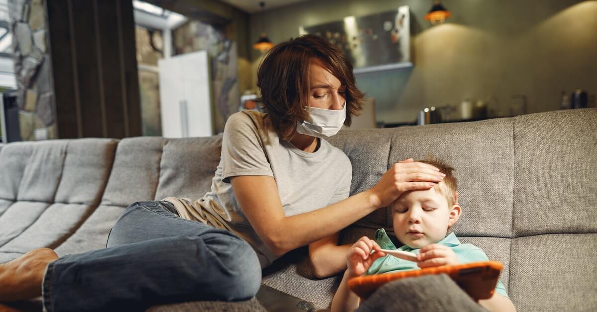 mother checking fever of baby boy or child by putting her hand on boy's head