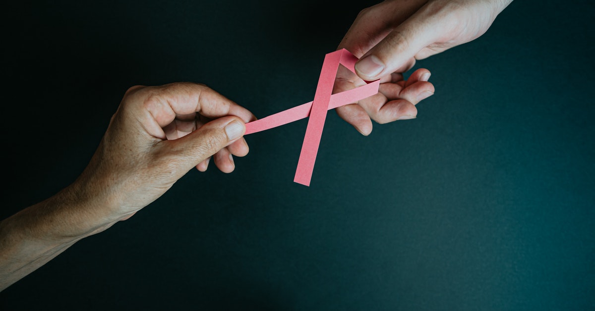 two men's hand holding cancer logo